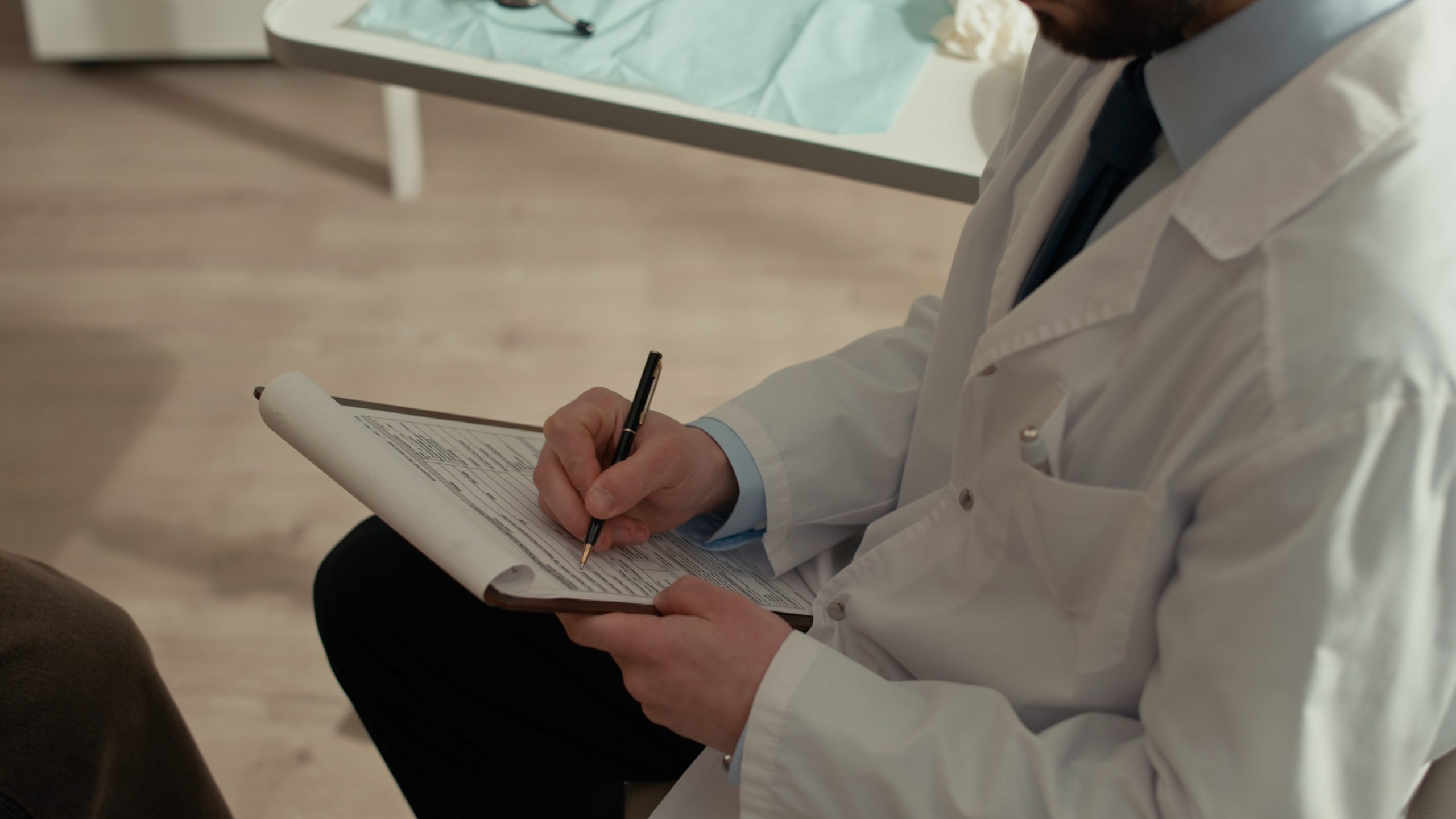 physician-taking-notes-on-clipboard-while-listening-to-patient physician taking notes on clipboard while listening to patient
